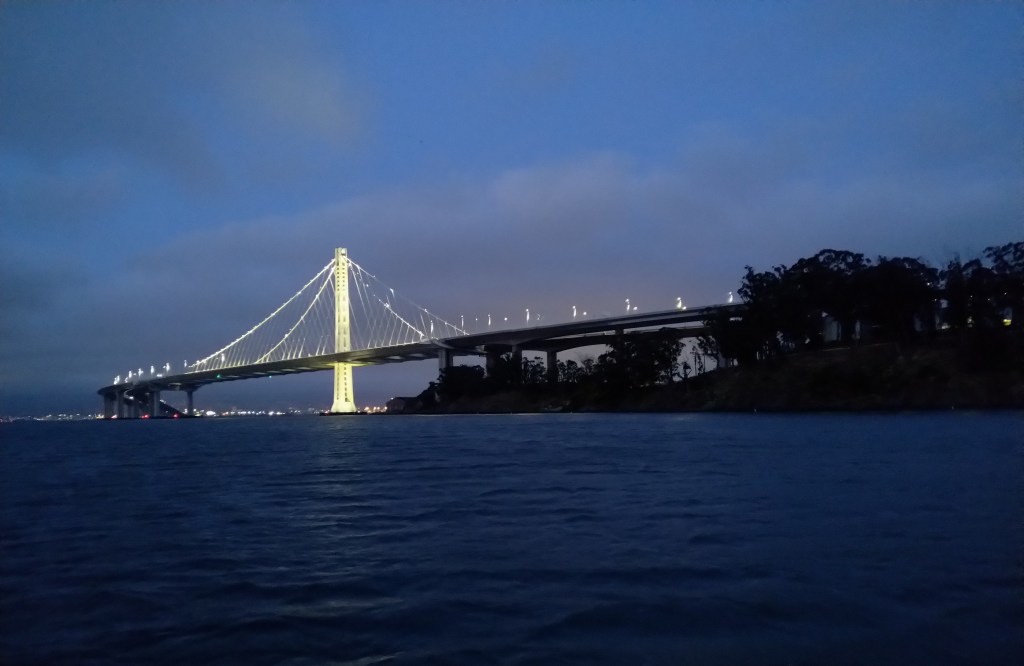 The Oakland span of the San Francisco Bay Bridge is seen lit up as darkness falls.