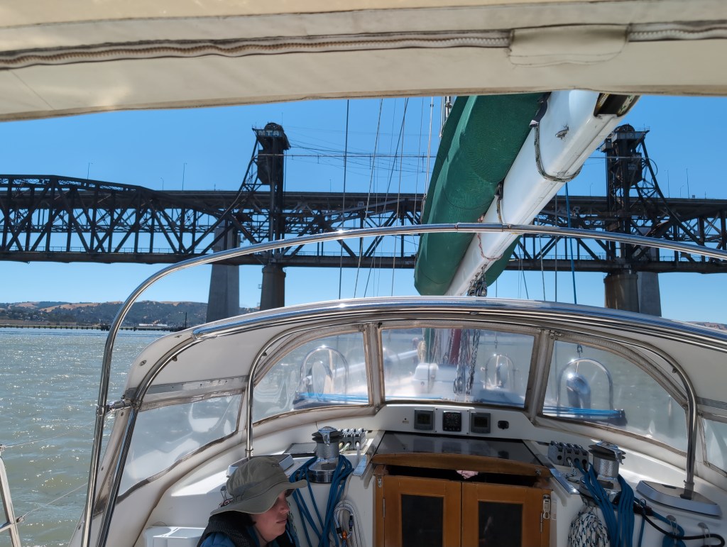 Tiffany sits in the cockpit as the boat approaches a low railroad bridge.