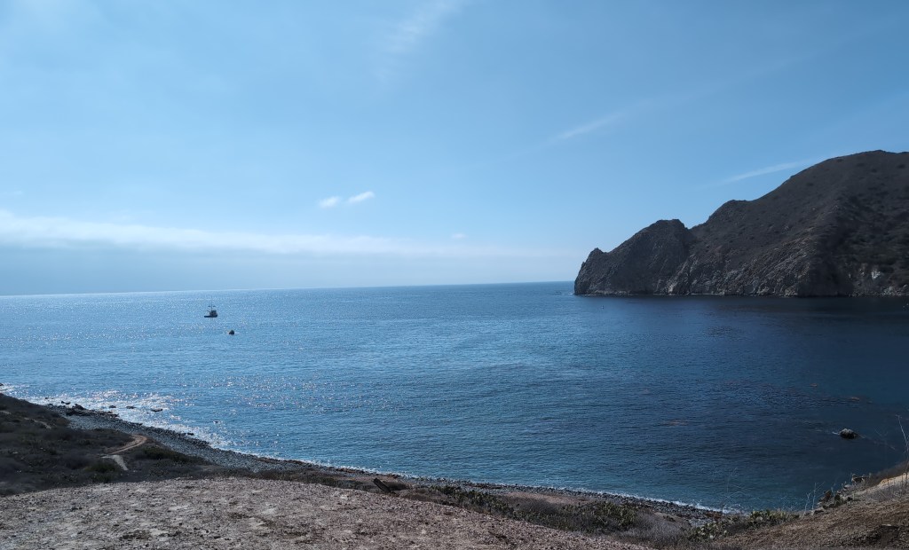 A calm harbor surrounded by hills reaches out toward the sea.