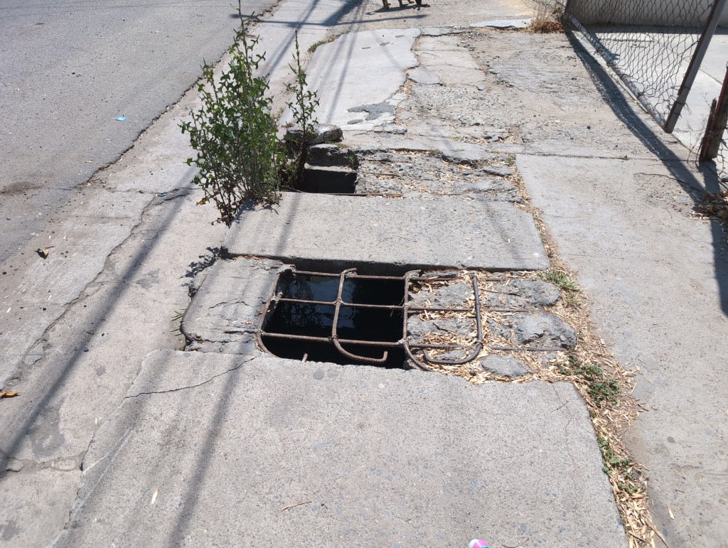 A rusted rebar lattice stands as the only reminder of where a cement access lid once resided.